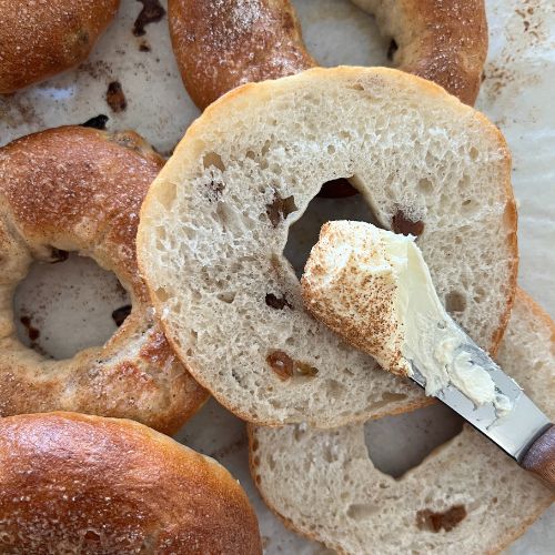 Spreading butter on a sourdough bagel.