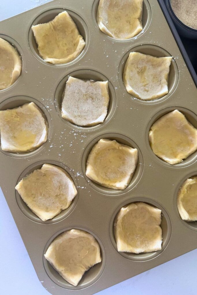 Squares of sourdough puff pastry arranged in a gold 12 hole muffin pan.