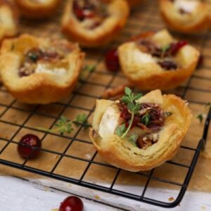 An image of sourdough puff pastry tarts filled with Brie cheese and cranberry orange jam garnished with fresh thyme.