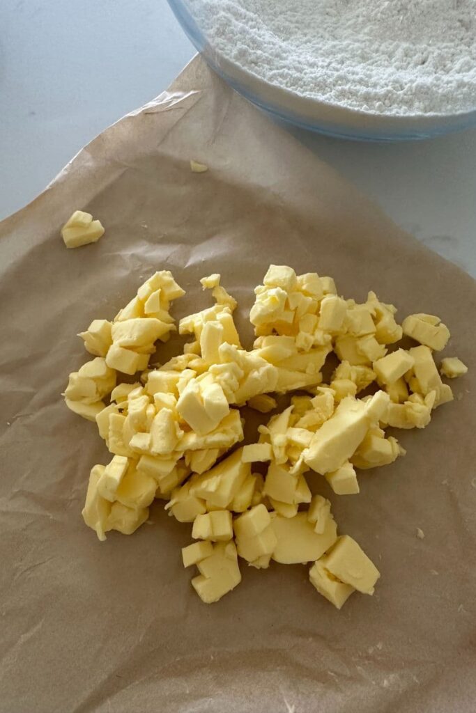 Small cubes of butter sitting on a sheet of parchment paper.