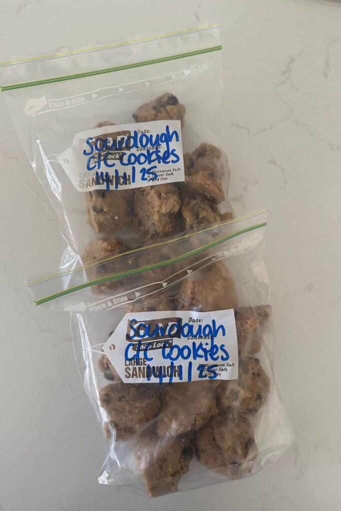 Scoops of sourdough cookie dough that has been snap frozen and placed into two ziploc bags. The ziploc bags have been labelled in blue marker with the contents and date.