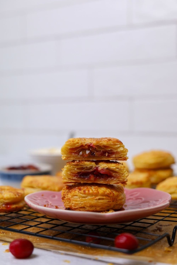 A stack of sourdough apple and cranberry hand pies sitting on a pink plate.