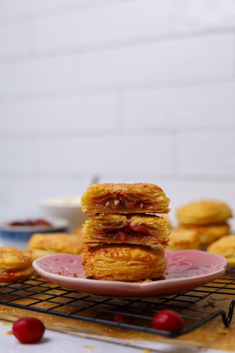 A stack of sourdough apple and cranberry hand pies sitting on a pink plate.