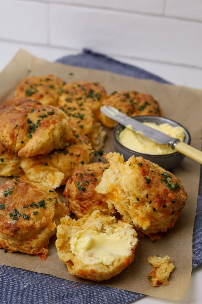 A close up of a sourdough cheddar biscuit that has been split open and buttered.