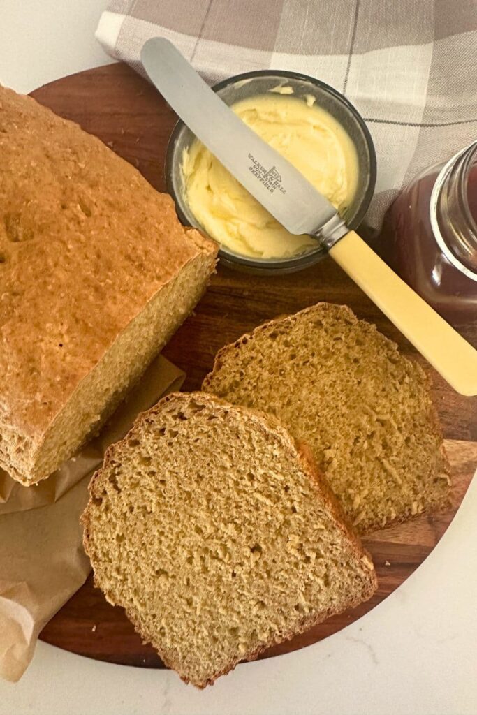 Slices of sourdough Irish brown bread shown next to a small dish of butter and a butter knife.