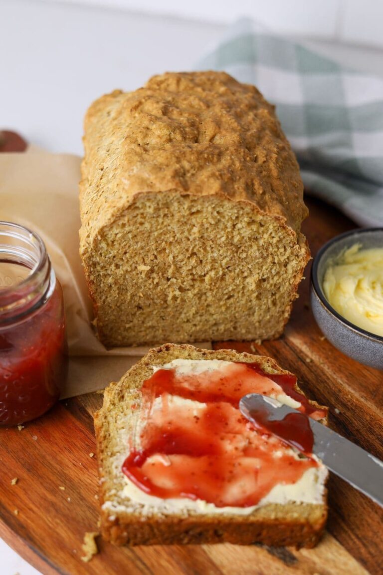 Loaf of sourdough Irish brown bread sliced and slathered in butter and strawberry jam.