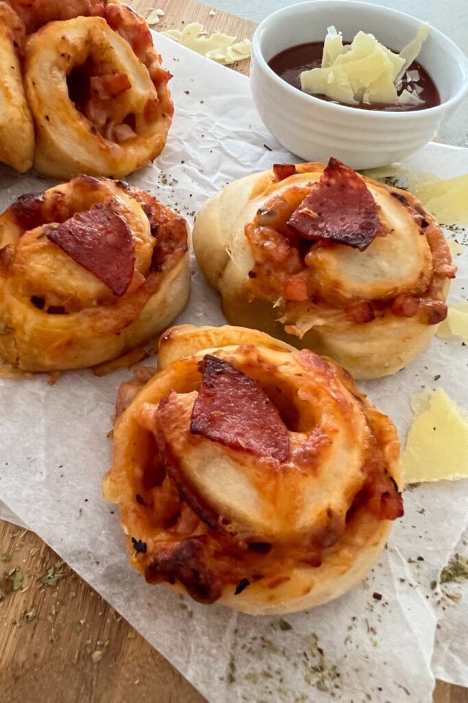 3 sourdough pizza rolls that have been baked and are displayed with a dish of homemade tomato pizza sauce.