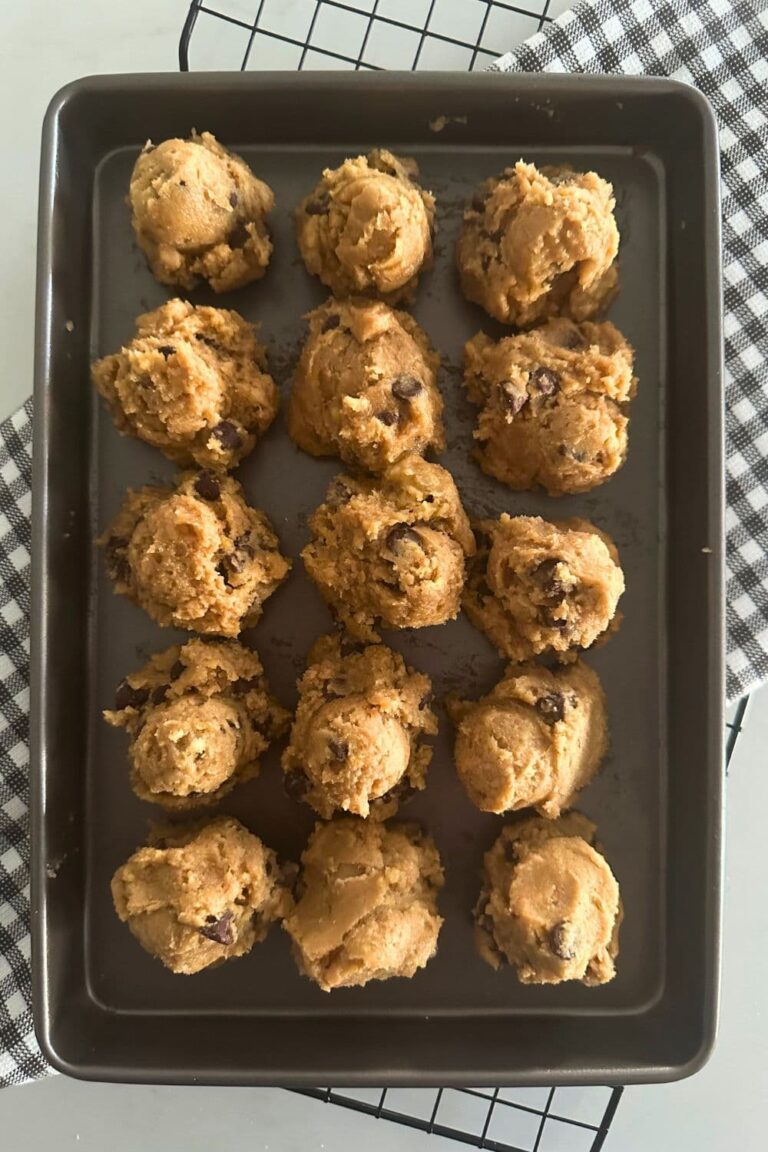 A baking tray containing scoops of sourdough chocolate chip cookie dough that is ready for the freezer.