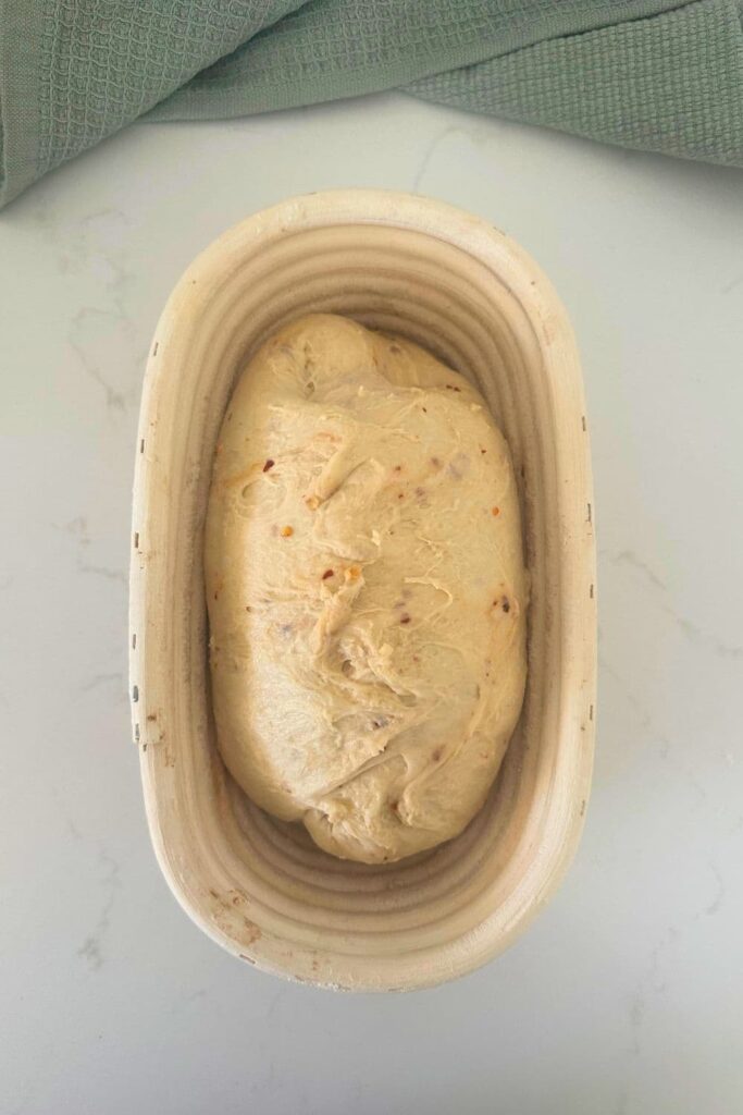 A loaf of hot honey sourdough bread dough in a banneton.