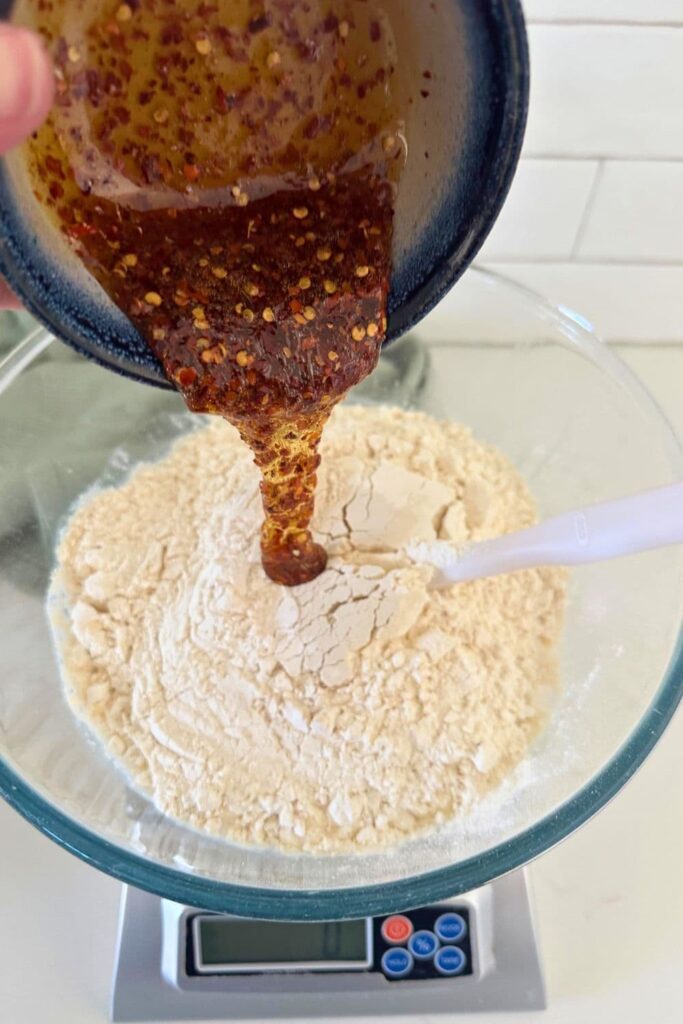 A bowl of hot honey being poured into a bowl of flour.