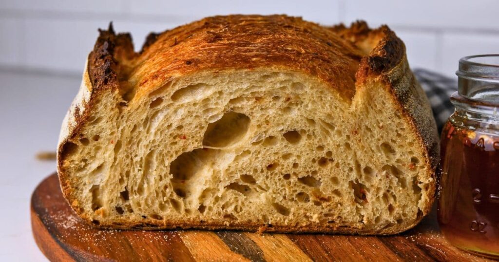 A loaf of hot honey sourdough bread that has been sliced in half so you can see the crumb shot.