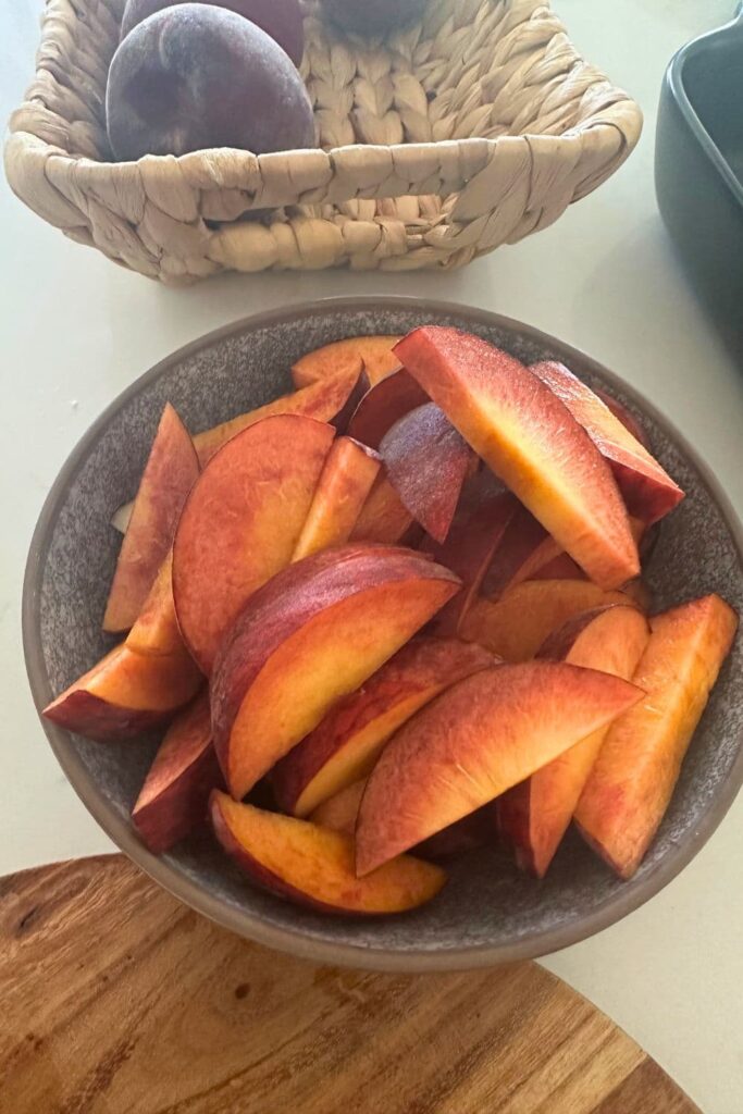 A bowl of clingstone peaches that have been chopped into slices.