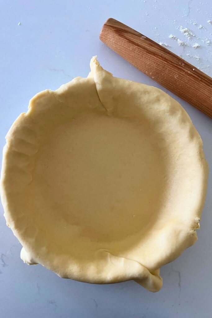 A sourdough pie crust rolled out in a pie dish ready to freeze.