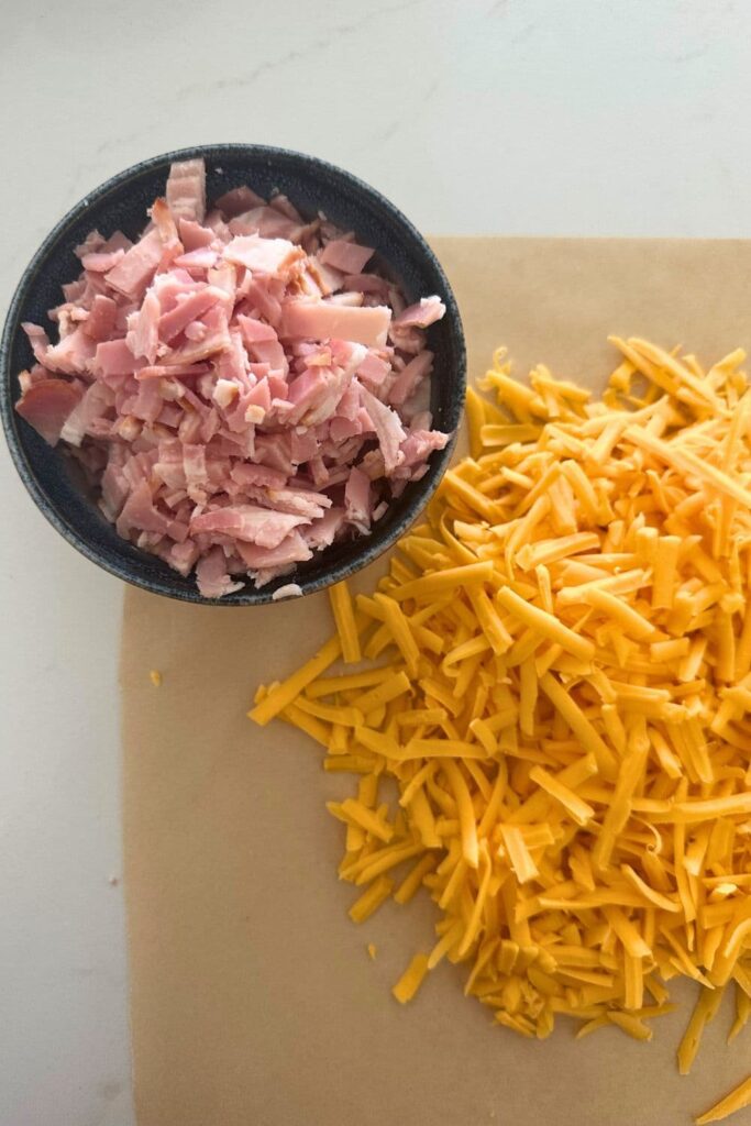 A bowl of diced bacon and shredded cheddar cheese.