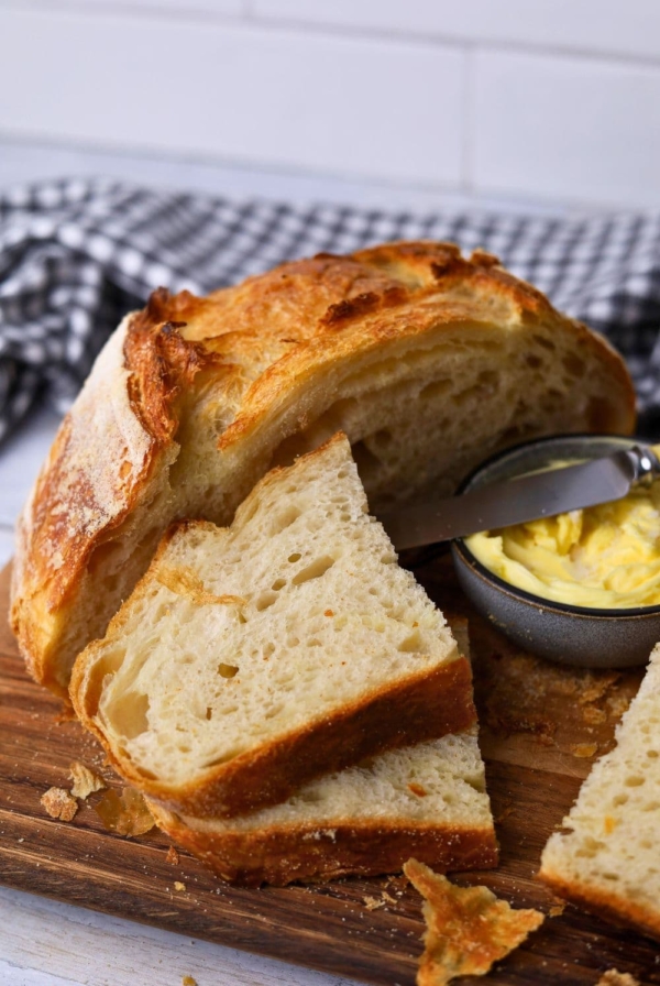Slices of sourdough croissant bread laid out on a wooden board with a small dish of butter.