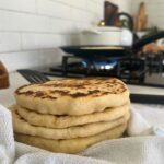 A stack of sourdough pita bread wrapped in a dish towel.