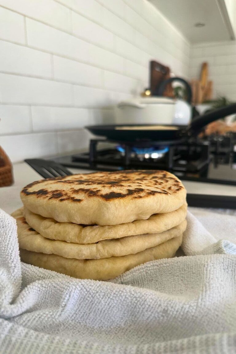 A stack of sourdough pita bread wrapped in a dish towel.