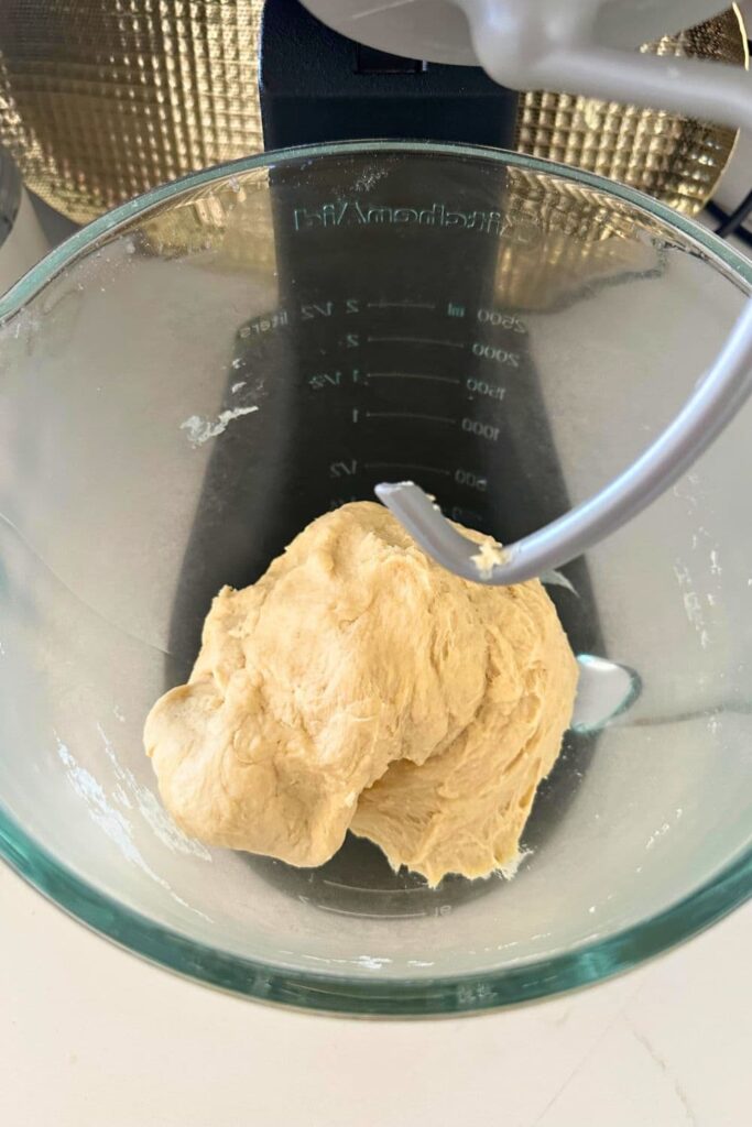 A glass Kitchenaid bowl and dough hook with the dough for sourdough pita bread having just been kneaded.