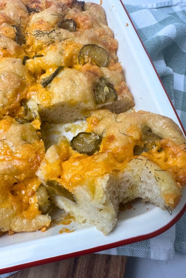 A red borded cream enamel baking dish filled with sourdough dill pickle cheddar focaccia bread.