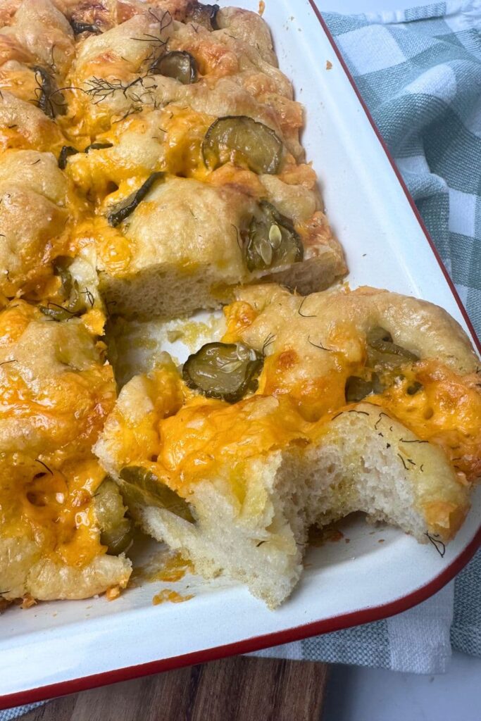 A red borded cream enamel baking dish filled with sourdough dill pickle cheddar focaccia bread.