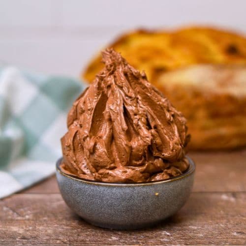 A small grey bowl of whipped chocolate butter sitting in front of a loaf of sourdough bread.