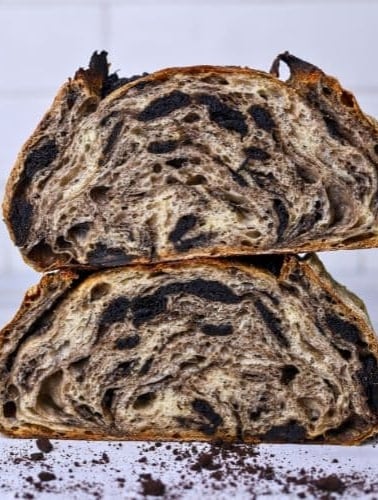 Two halves of a loaf of cookies and cream sourdough bread stacked on top of each other so you can see the crumb inside.