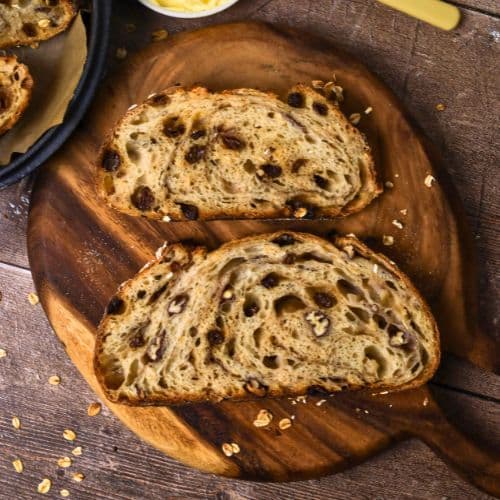 2 slices of sourdough apple crisp loaf set out on a round wooden board.