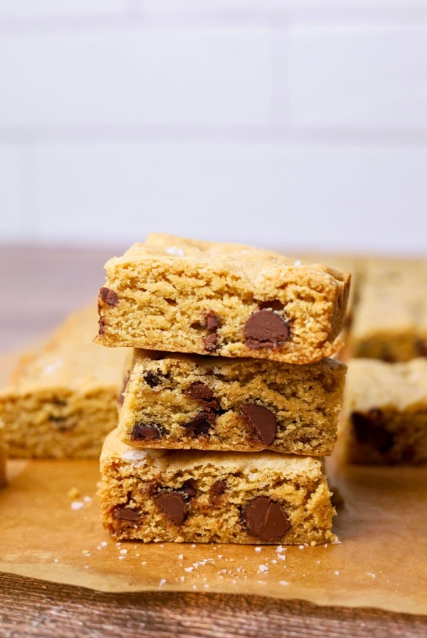 3 sourdough chocolate chip cookie bars stacked on top of each other. You can see the fudgy inside and all the chocolate chips.