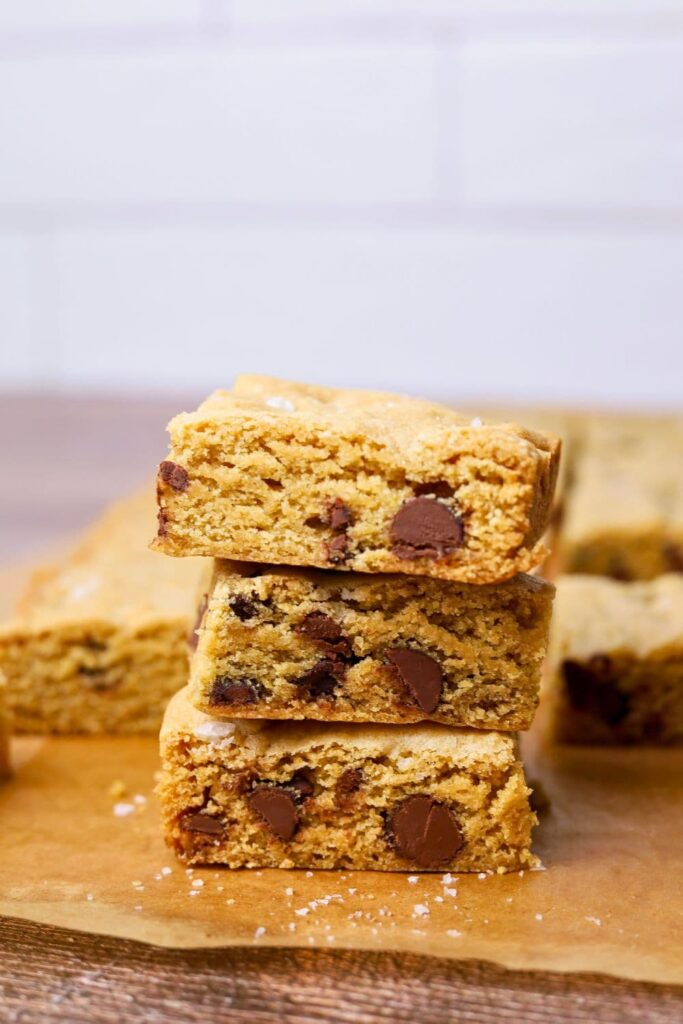 3 sourdough chocolate chip cookie bars stacked on top of each other. You can see the fudgy inside and all the chocolate chips.