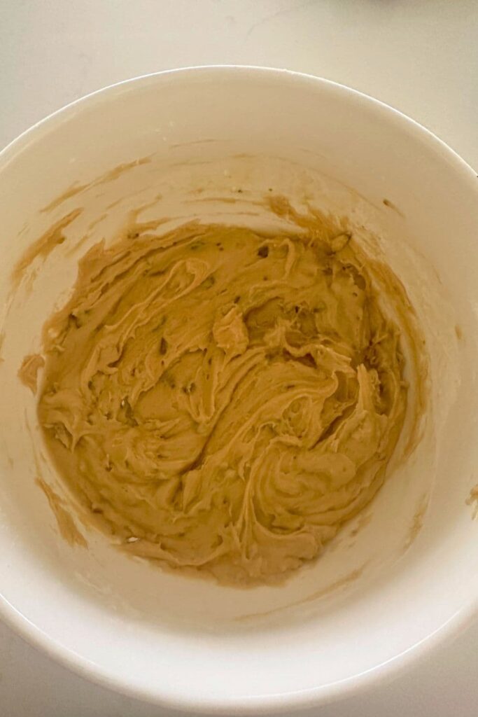 Wet cookie dough for sourdough honey and pistachio cookies in a cream bowl.