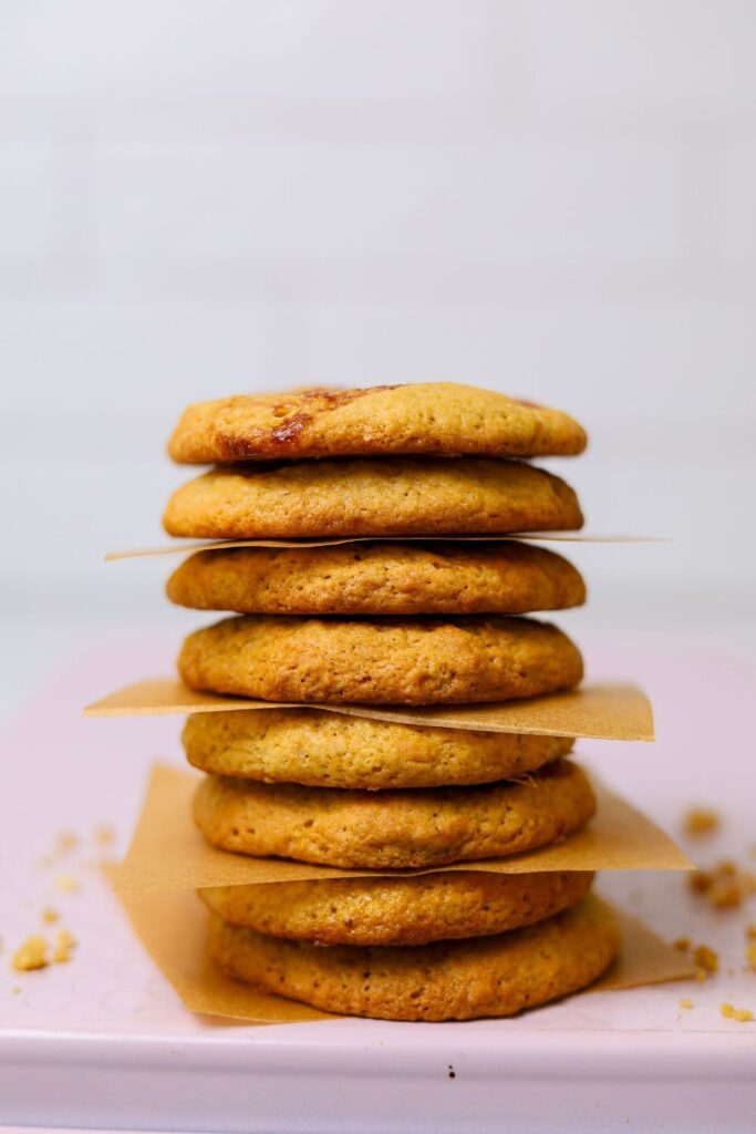 A stack of sourdough peanut butter and jelly cookies balanced on a pale pink baking tray.