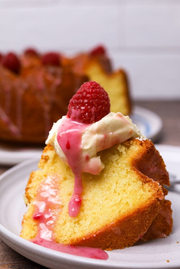 sourdough pound cake slice with butter, glaze and a raspberry on a plate.