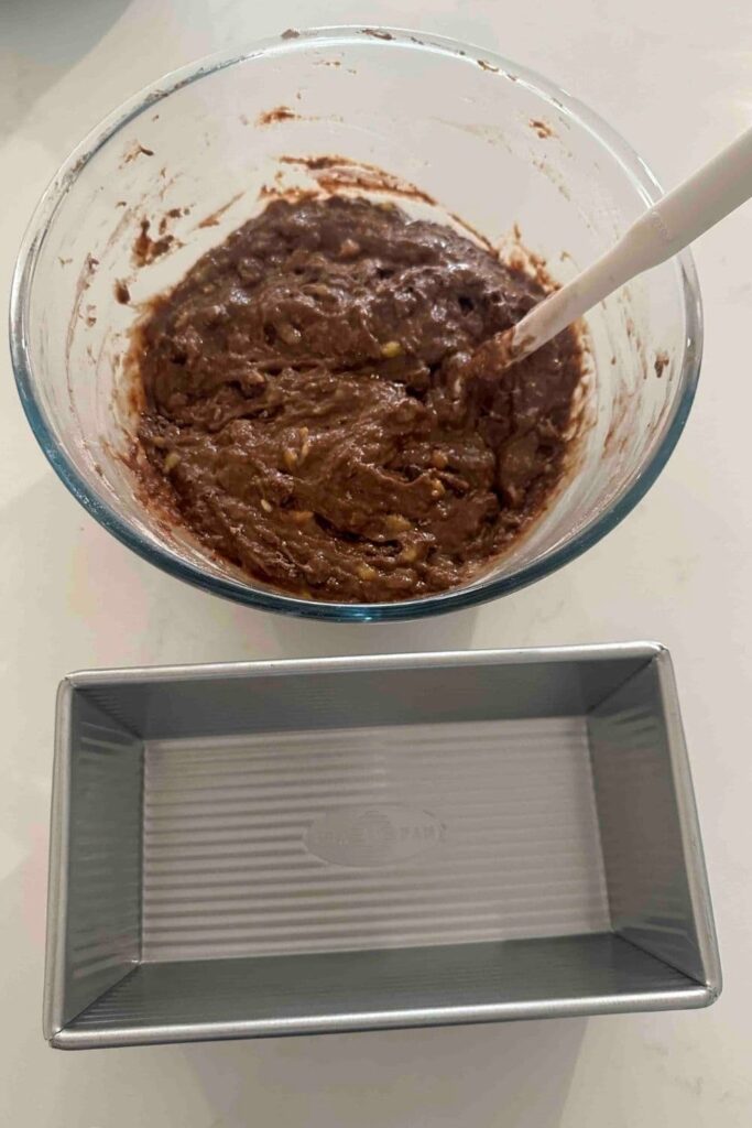 Batter in a bowl, next to the loaf pan for double chocolate sourdough banana bread.