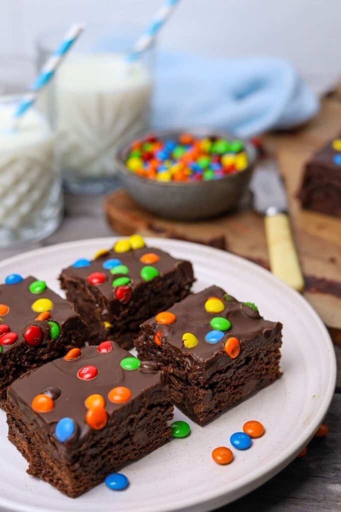 Sourdough cosmic brownies sliced on a plate with two glasses of milk in background.