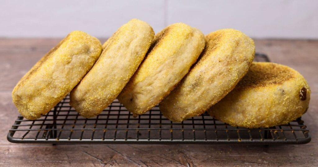 Sourdough discard cinnamon raisin English muffins standing on edge together on a cooling rack.