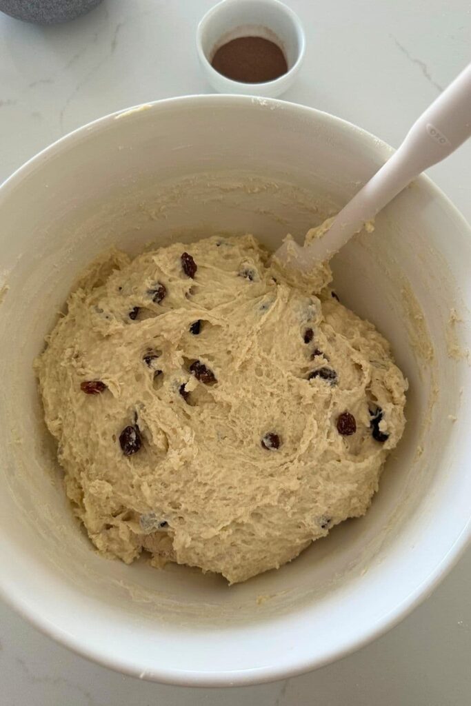 Sourdough discard cinnamon raisin English muffin dough being mixed together in a bowl with a spoon.