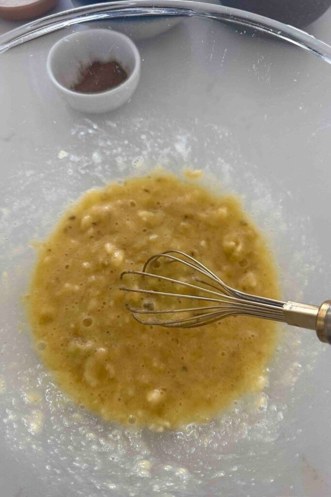 Mashed bananas with vanilla and an egg mixed in a glass bowl to make sourdough Hawaiian banana bread.