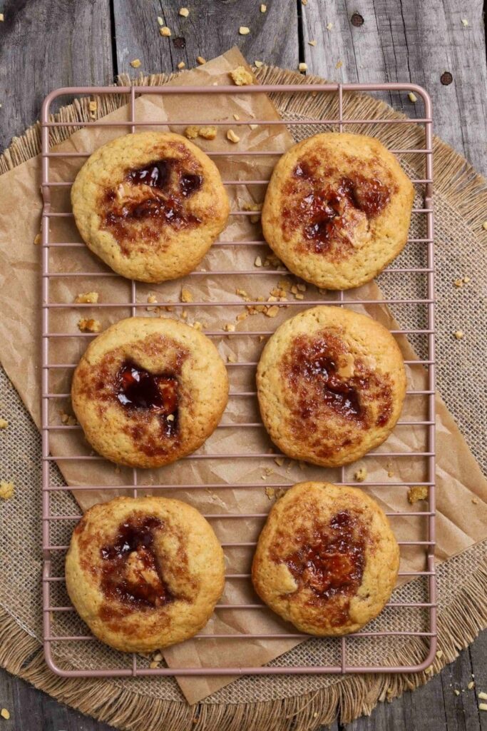 fresh baked sourdough peanut butter and jelly cookies on cooling rack over parchment paper.
