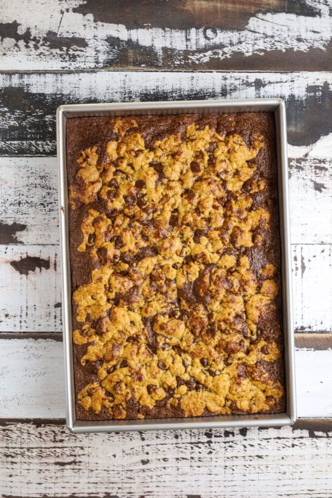 A tray of sourdough brookies that has just been baked and removed from the oven and placed on a wooden board.