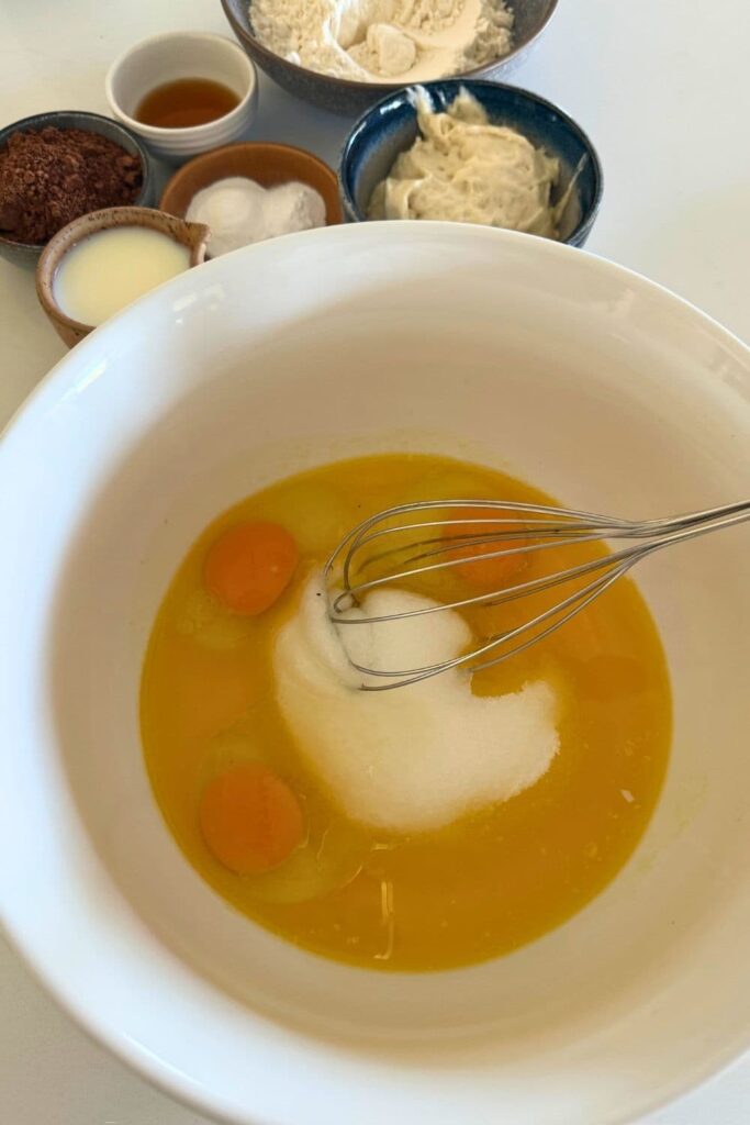 wet ingredients being mixed in bowl with a whisk for sourdough chocolate cupcakes.