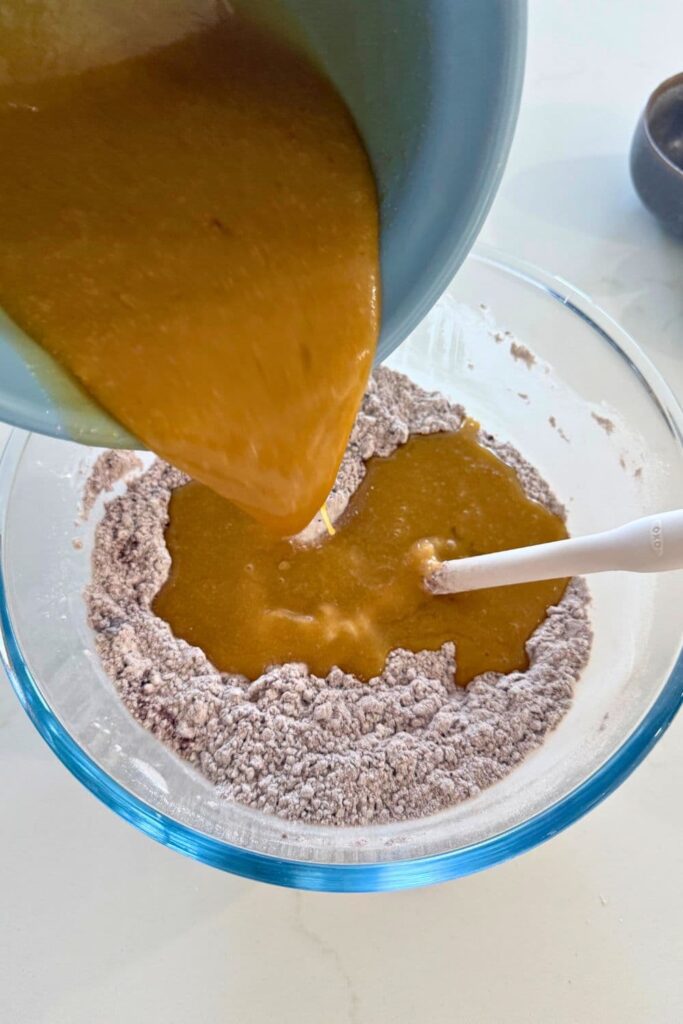 Pouring wet ingredients into dry ingredients to make the dough for sourdough Halloween cookies.