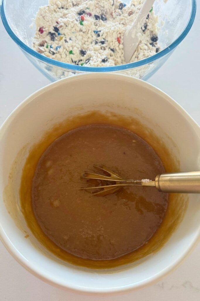 Wet ingredients for sourdough monster cookies mixed in a bowl with a whisk.