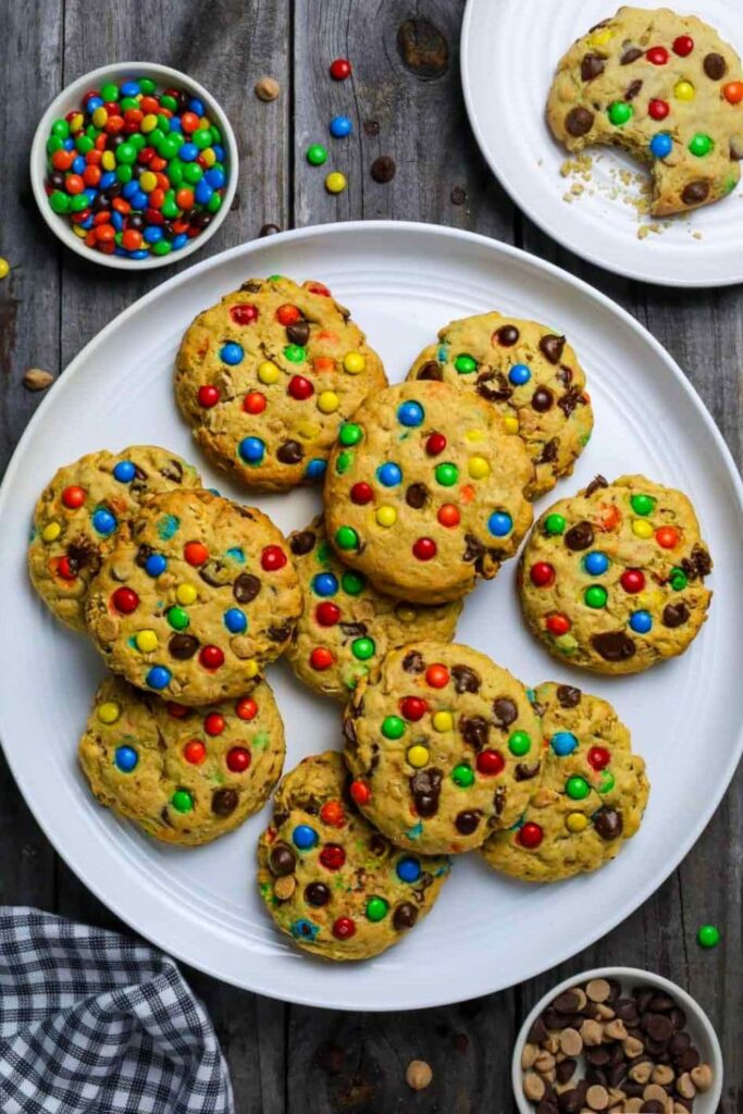 Large round white plate with sourdough monster cookies sitting on wooden table.