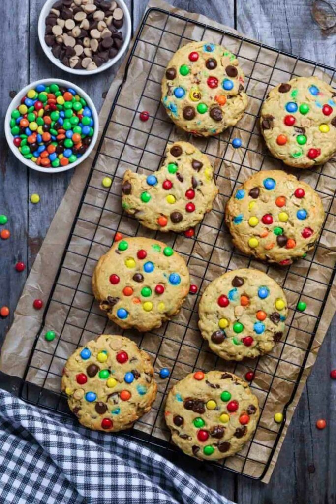 sourdough monster cookies on a wire cooling rack with a bite of one cookie taken out.