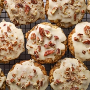 A whole batch of maple pecan sourdough oatmeal cookies with maple butter glaze on a wire cooling rack.