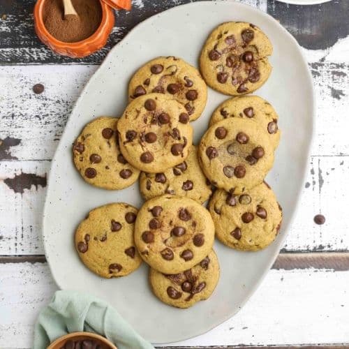 Sourdough pumpkin chocolate chip cookies on a serving plate on a wooden table.