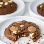 A large, bakery style, triple chocolate sourdough cookie that has a bite taken out of it.