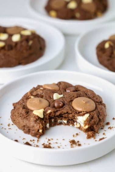 A large, bakery style, triple chocolate sourdough cookie that has a bite taken out of it.