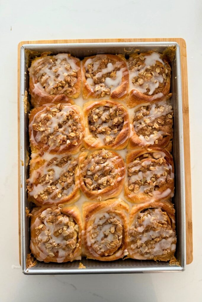 Fresh baked sourdough apple cinnamon rolls in pan with glaze on top.