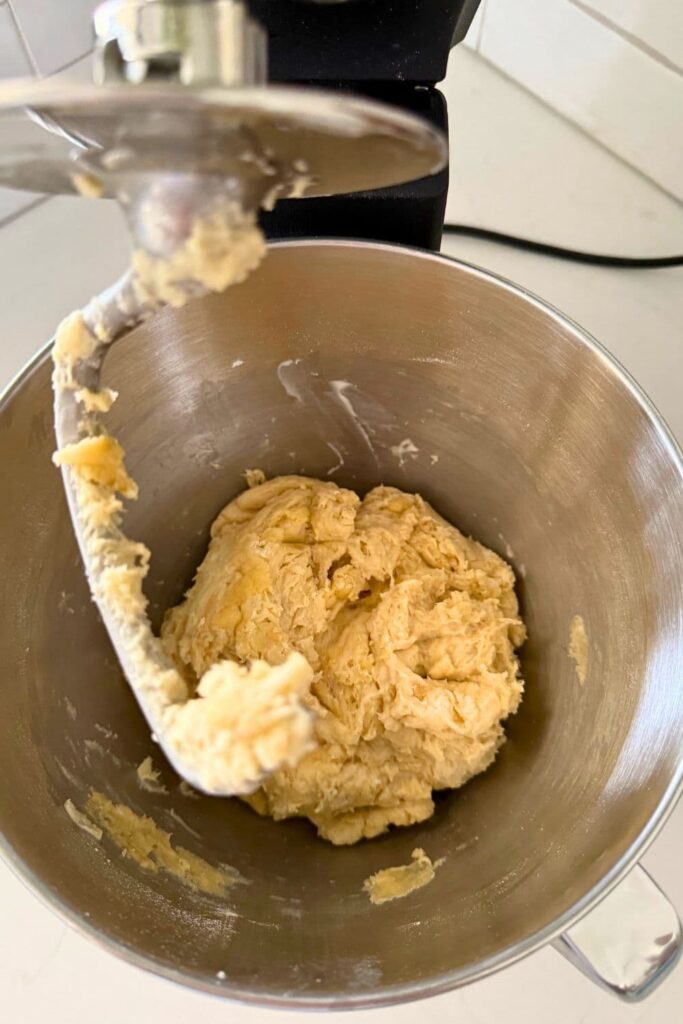 Sourdough burger bun dough being mixed with dough hook in stand mixer.